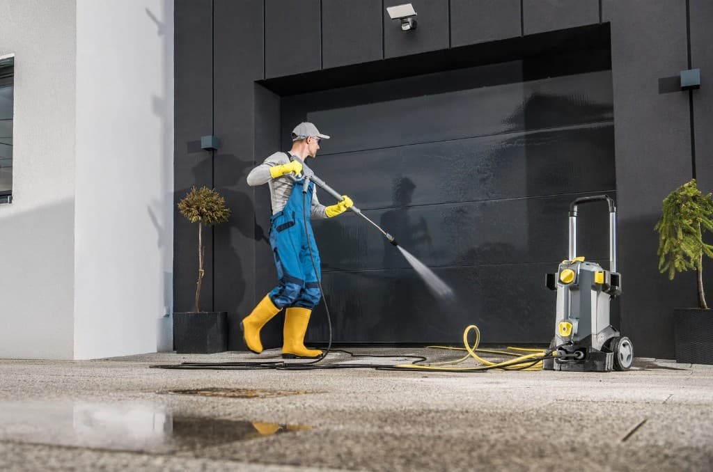 Worker pressure washing a commercial garage door