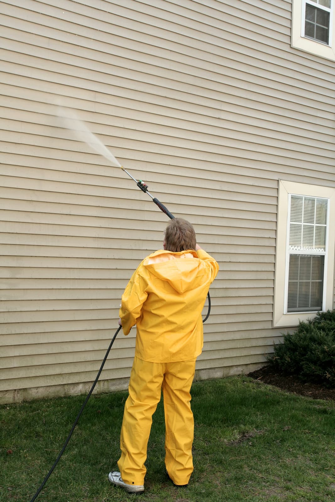 Precision Powerwash technician pressure washing a home exterior